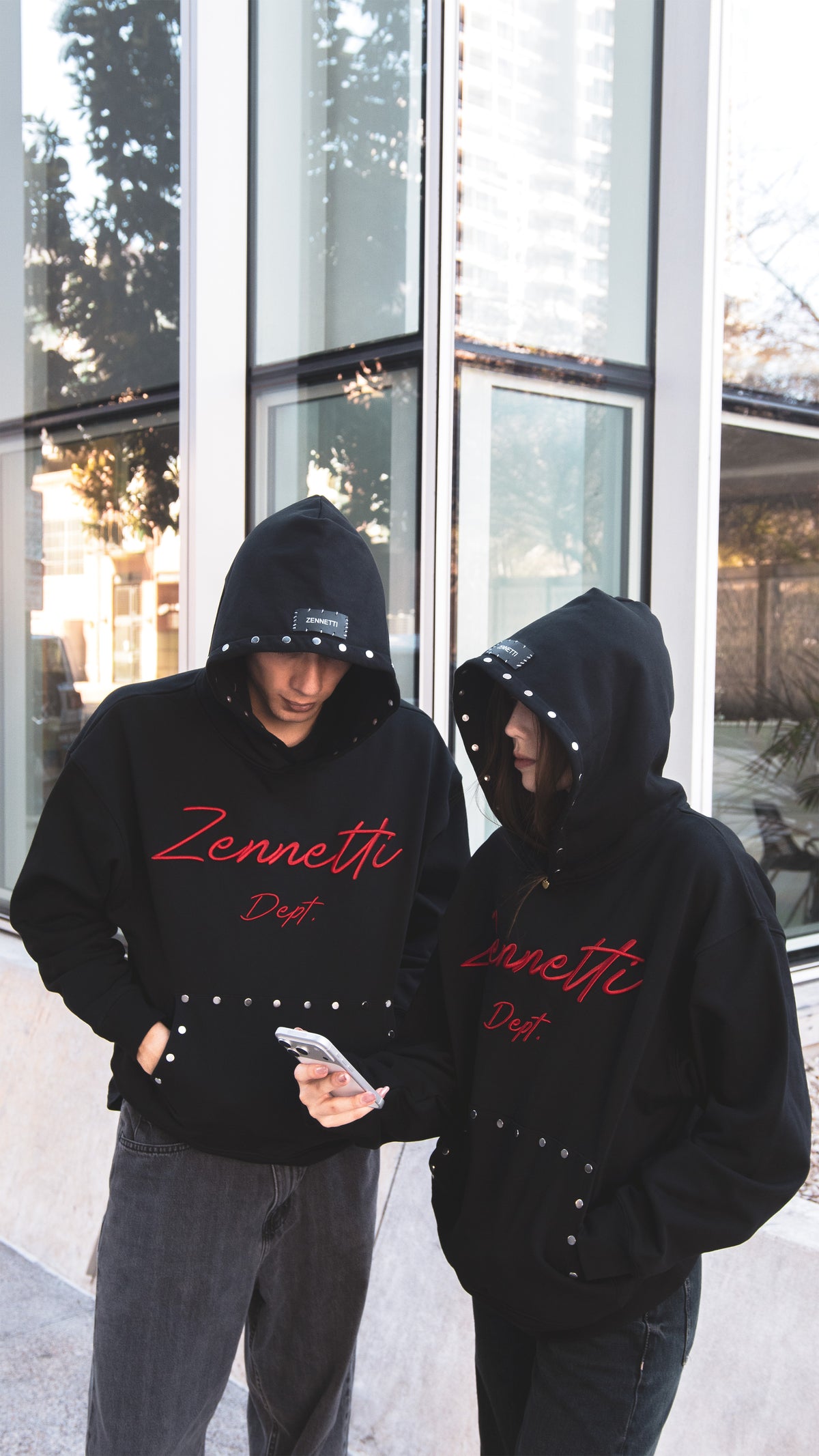 Detalle del logo Zennetti Dept. bordado en rojo y los remaches metálicos del bolsillo canguro